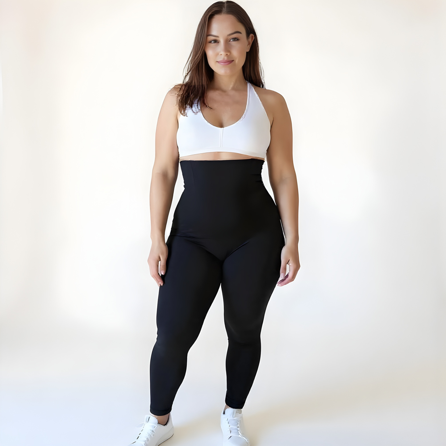 Woman wearing high-waisted black compression leggings and a white sports bra on a soft beige background — Scandinavian minimalist style by KORFORM.
