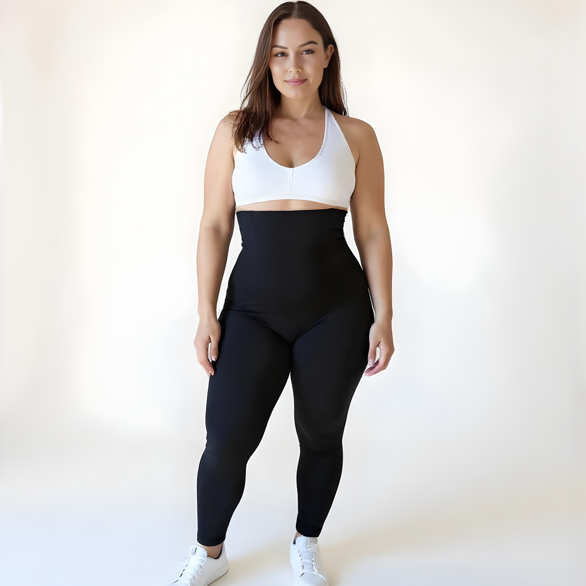 Woman wearing high-waisted black compression leggings and a white sports bra on a soft beige background — Scandinavian minimalist style by KORFORM.