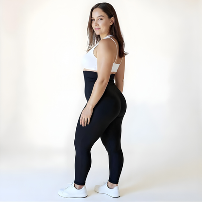 Woman wearing high-waisted black compression leggings and a white sports bra in a three-quarter pose, showing the sleek fit and sculpted confidence — KORFORM Scandinavian activewear.