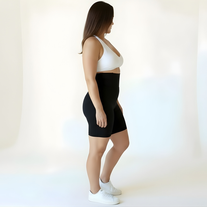 Side view of a woman wearing high-waisted black compression shorts and a white sports bra, showing the supportive waistband and smooth matte finish — KORFORM Scandinavian design.